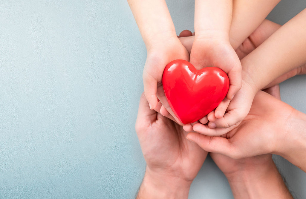 The adult and the child holding red heart.