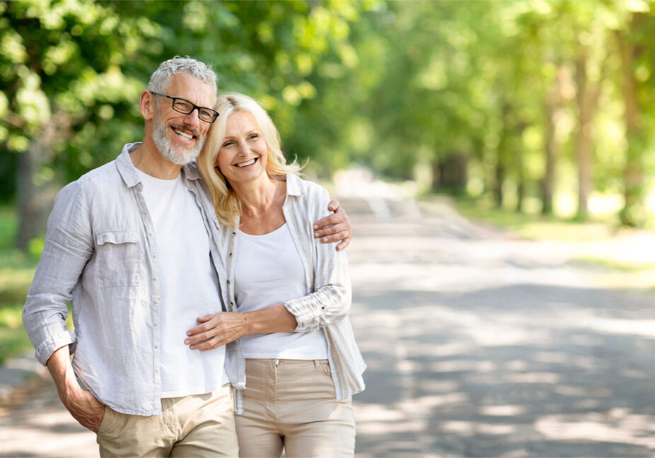Beautiful mature spouses hugging outdoors while walking in summer park